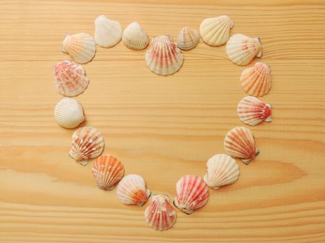Heart of seashells on a wooden background.