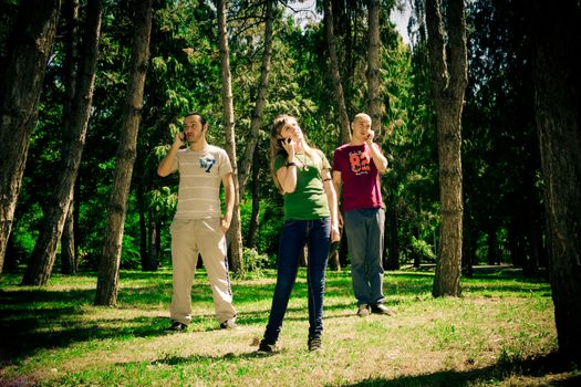 three teenagers talking to the phone in the forest