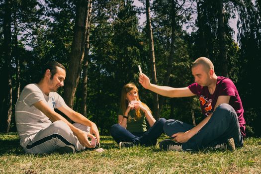 Three friend having fun by playing cards in the forest