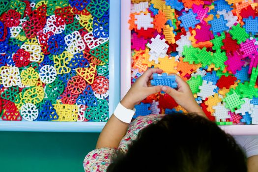 An Asian Chinese girl solving puzzle at indoor playground.