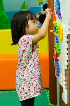 An Asian Chinese girl solving puzzle at indoor playground.