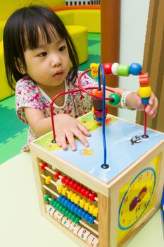 An Asian Chinese girl solving puzzle at indoor playground.