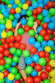 Asian Chinese girl hide in colorful ball pool at indoor playground.