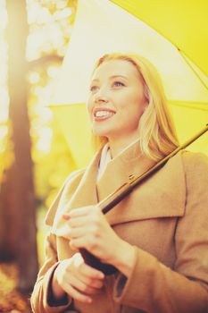 holidays, seasons, travel, happy people concept - smiling woman with yellow umbrella in the autumn park