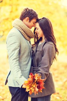 holidays, love, travel, relationship and dating concept - romantic couple kissing in the autumn park