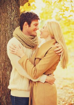 holidays, love, relationship and dating concept - romantic couple kissing in the autumn park