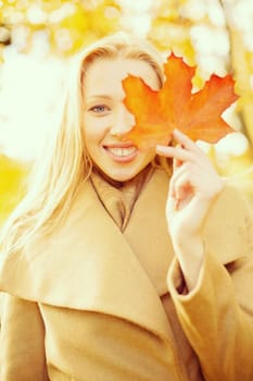 holidays, seasons, travel, happy people concept - smiling woman with red marple leaf in the autumn park