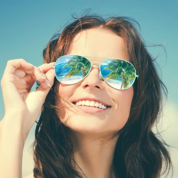 holidays, travel, vacation and happiness concept - beautiful woman in sunglasses with beach reflection