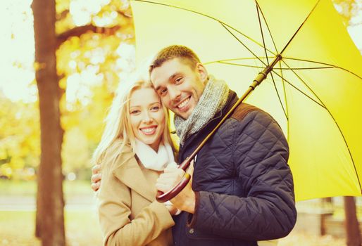 holidays, love, travel, relationship and dating concept - romantic couple with umbrella in the autumn park