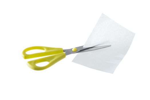 A pair of yellow scissors cutting a piece of white paper isolated on a white background.