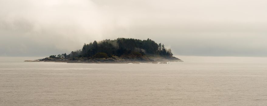 A lonely island along the inside passage made of granite covered in trees