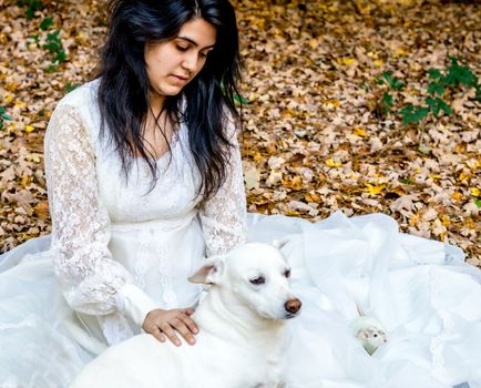 Latina teenage girl sitting outside in the autumn leaves with her pet dog and rat