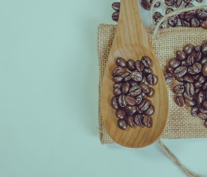 Coffee beans and wooden spoon on sack surface.Filter effect retro vintage style