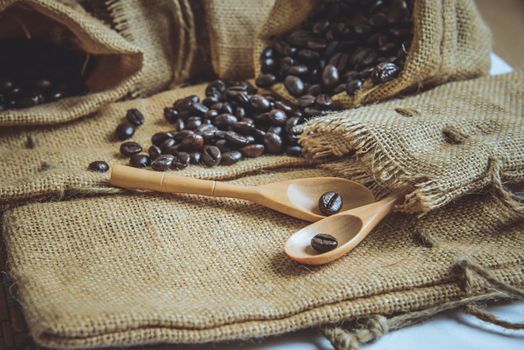 Vintage photo of Coffee beans and wooden spoon on sack surface.