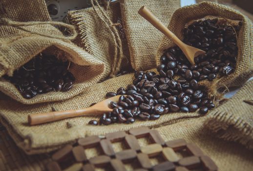 Vintage photo of Coffee beans and wooden spoon on sack surface.