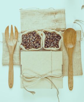 Coffee beans wooden spoon and fork on sack surface.Filter effect retro vintage style