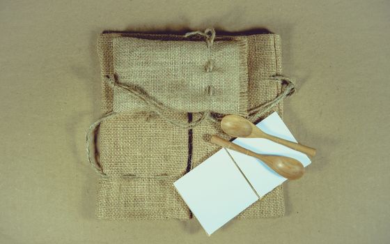 Notepad and wooden spoon on sack surface background.