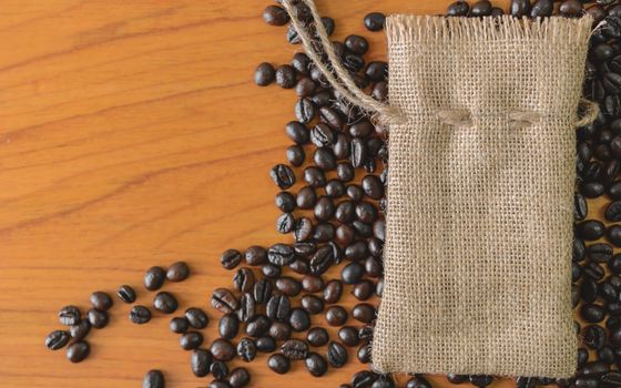 Sackcloth and coffee beans on old wooden table.top view point