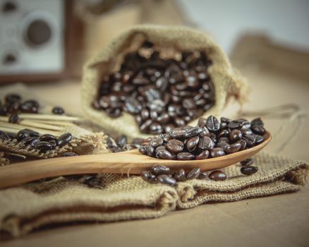 Vintage photo of Coffee beans and wooden spoon on sack surface, Soft focus.