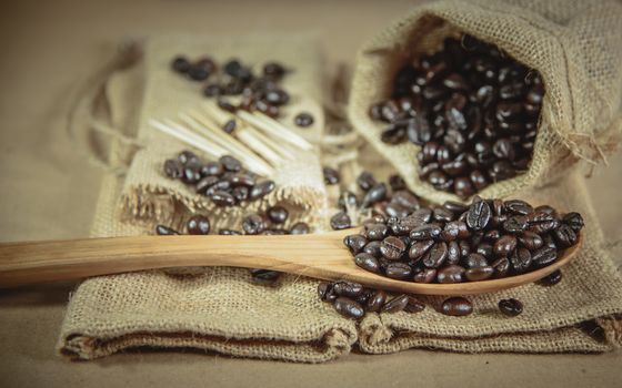 Vintage photo of Coffee beans and wooden spoon on sack surface, Soft focus.