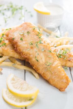 Fish and chips. Fried fish fillet with french fries on bright wooden background. Fresh cooked with hot steams.