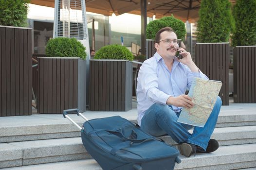 Trendy adult man in the town with touristic map outdoors.