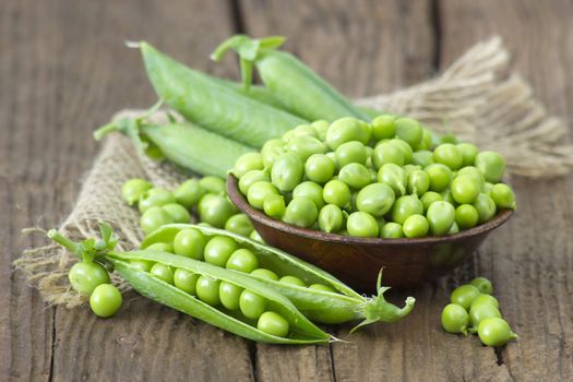 a bowl full of green peas on wooden background