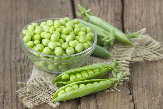 a bowl full of green peas on wooden background