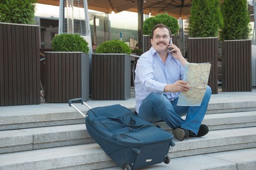 Trendy adult man in the town with touristic map outdoors.