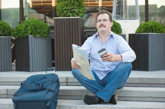 Trendy adult man in the town with touristic map outdoors.