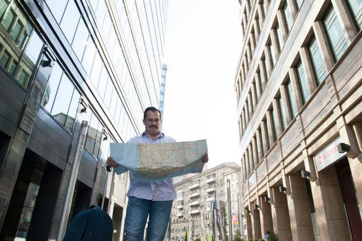 Man with blue bag lookig the way by city plan