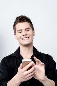 Casual young man using his smartphone over grey