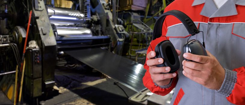 Worker with protective headphone at man hands at industrial factory