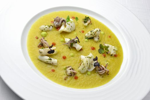 Fish Dish Cream of Jerusalem artichokes with saffron and squid with Herbs in white plate