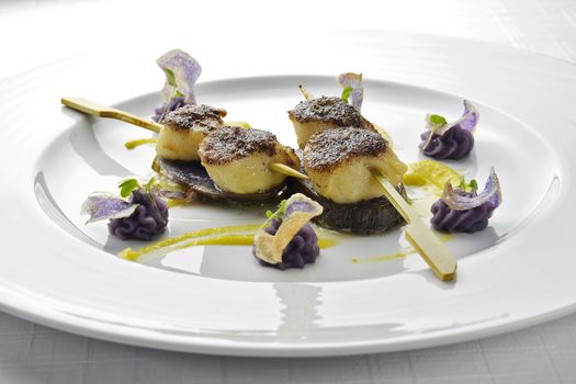 Fish Dish Skewer of Scallops Crusted with black Rice and Purple Potatoes in white plate