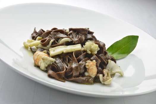 Pasta Dish Chocolate Fettuccine with Prawns and Cuttlefish in white plate