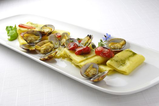 Pasta Dish Paccheri Macaroni with Clams Grilled Tomatoes and Basil Sauce in long white plate