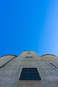 Looking up towards the top of a large silo against blue sky.