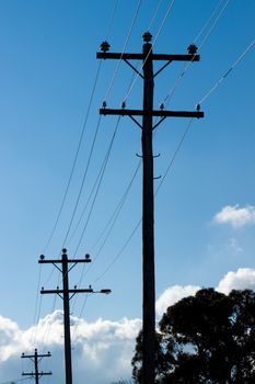 Silhouette of Overhead Power Lines and Poles with cloudy skies.