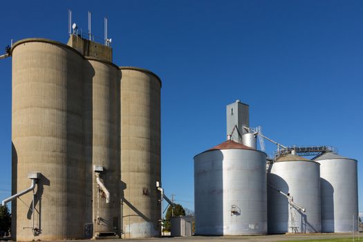 Large concrete and steel silos on blue sky.