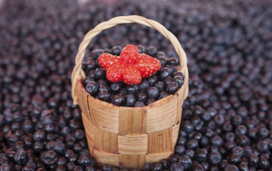 Fresh blueberries with a little basket of strawberries on the market.