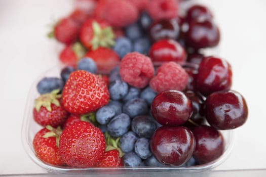 Fresh  raspberries strawberries cherries blueberries in the box on the market.