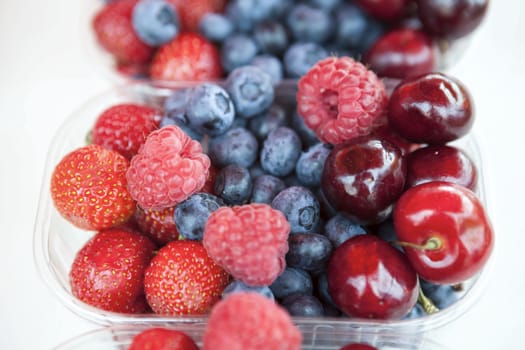 Fresh  raspberries strawberries cherries blueberries in the box on the market.