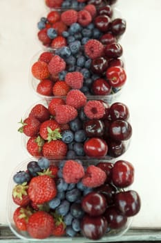 Fresh  raspberries strawberries cherries blueberries in the box on the market.