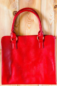 Female red bag from a genuine leather on a wooden background