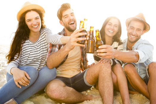 Friends having fun together at the beach and drinking a cold beer