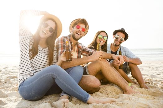 Friends having fun together at the beach and drinking a cold beer