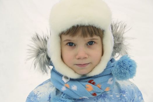 Winter portrait of adorable blue-eyed child girl in warm clothes