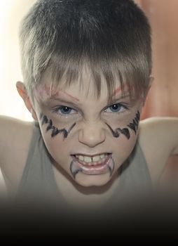 little cute boy with face painting bares his teeth