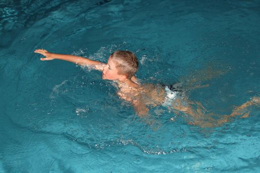 Close up of young boy swimming in pool.